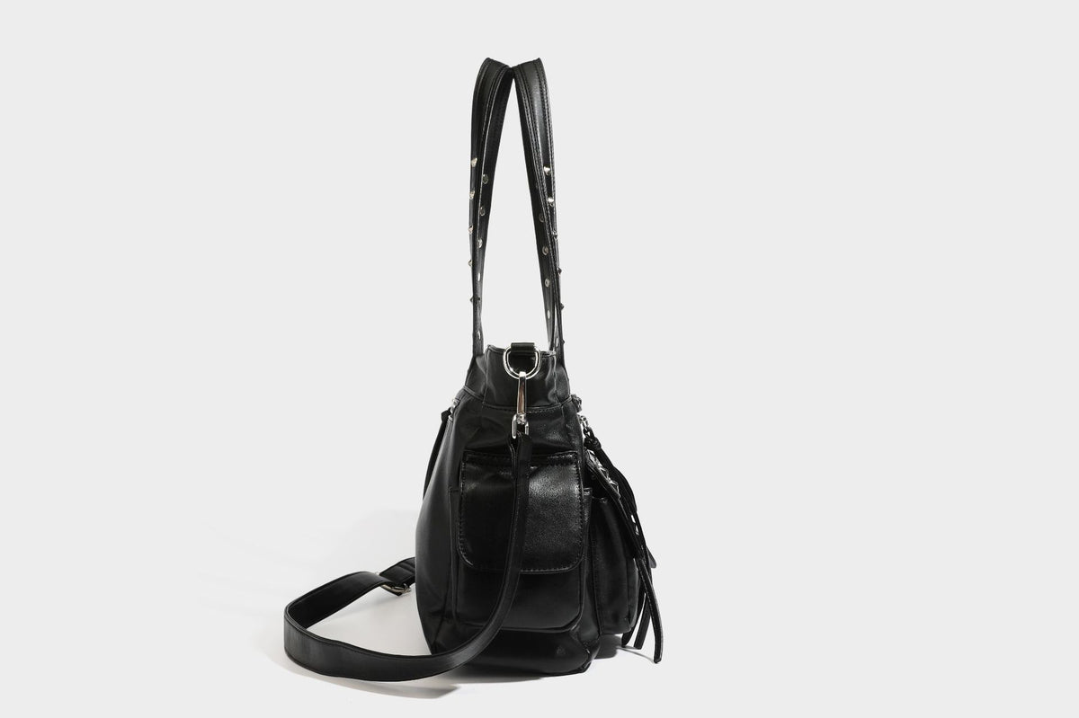 Black leather-look tote bag with silver pyramid studs on handles and front panel, multiple flap and zip exterior pockets