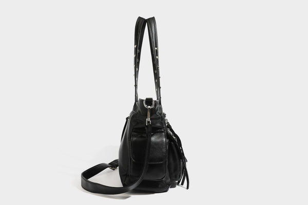 Black leather-look tote bag with silver pyramid studs on handles and front panel, multiple flap and zip exterior pockets