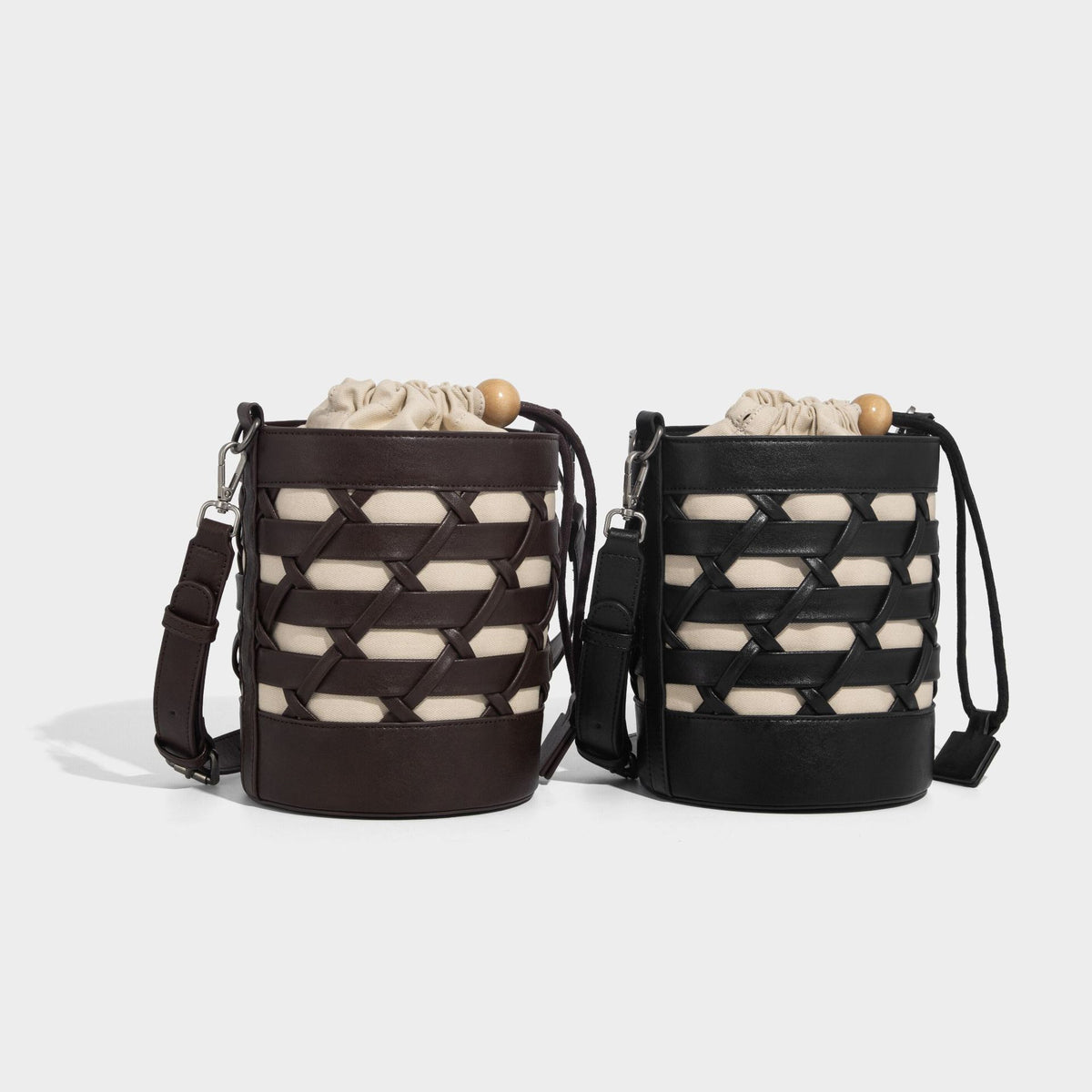 Small cylindrical woven lattice bucket bag with leather-look black trim, beige canvas body, wooden bead drawstring closure