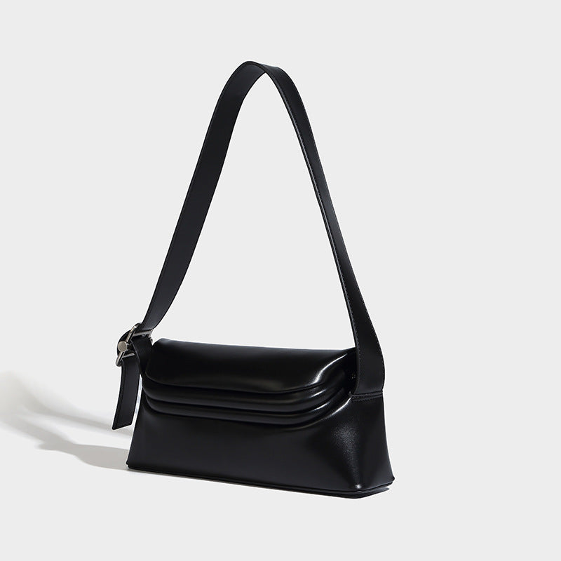 Compact structured baguette shoulder bag with smooth leather-look finish, zip top, and adjustable silver-buckle strap, detail