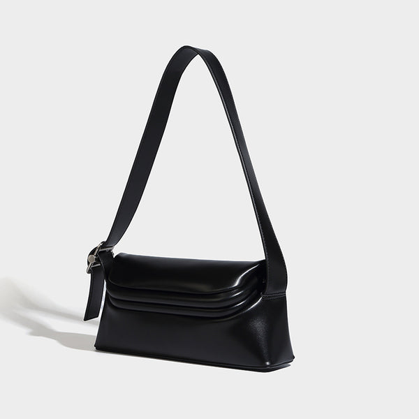 Compact structured baguette shoulder bag with smooth leather-look finish, zip top, and adjustable silver-buckle strap, detail