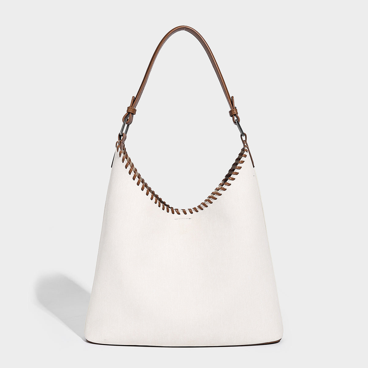 Denim-blue hobo tote with white leather-look shoulder strap, contrast whipstitch trim along curved open top, and silver-tone