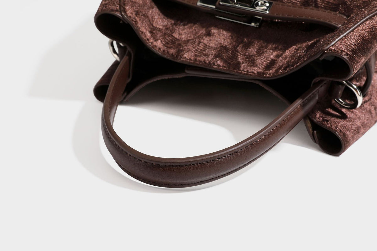 Small structured bucket satchel in embossed velvet-texture fabric with silver turn-lock hardware, rounded top handle, and
