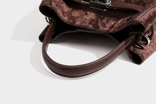 Small structured bucket satchel in embossed velvet-texture fabric with silver turn-lock hardware, rounded top handle, and