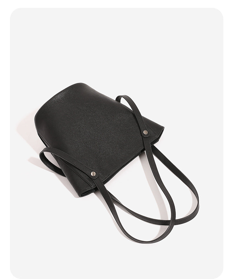Structured black leather-look bucket tote bag with slim shoulder straps, silver-tone stud hardware, and tapered body, detail