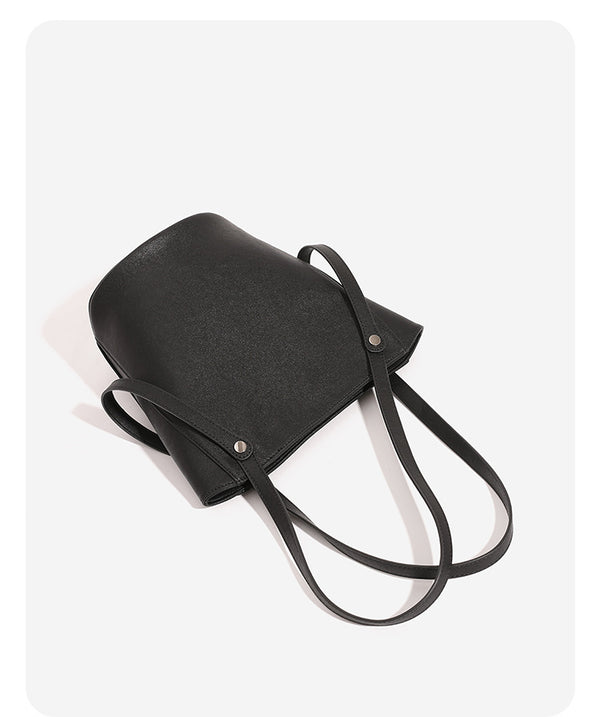 Structured black leather-look bucket tote bag with slim shoulder straps, silver-tone stud hardware, and tapered body, detail