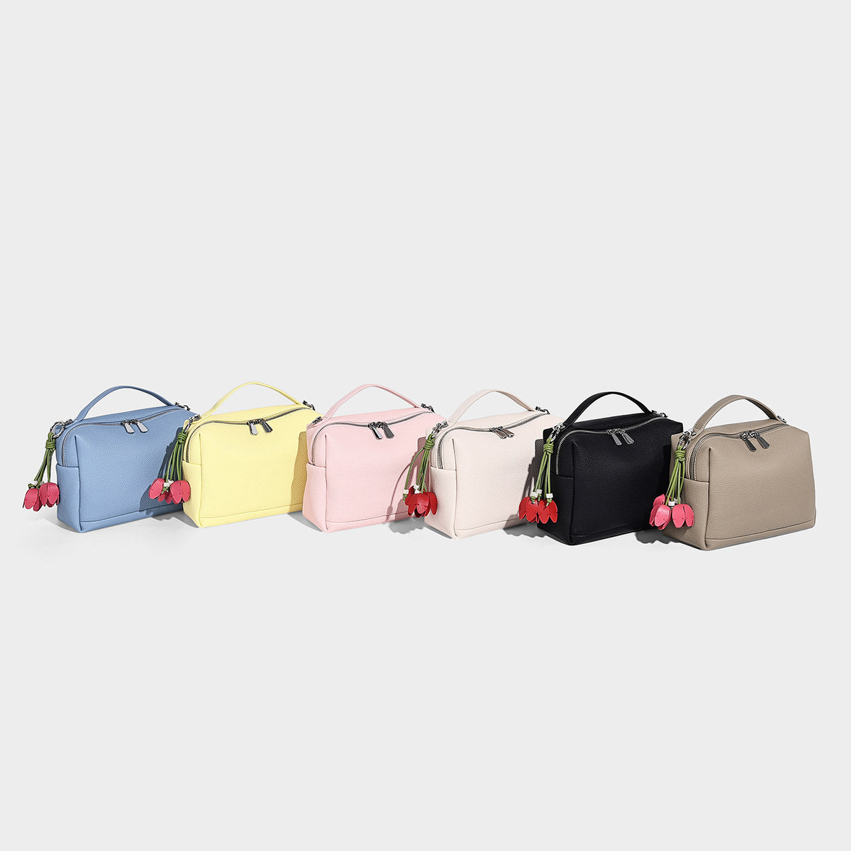 Small structured pebbled top-handle crossbody bag with zip closure, silver-tone hardware, and optional hanging tassel charm