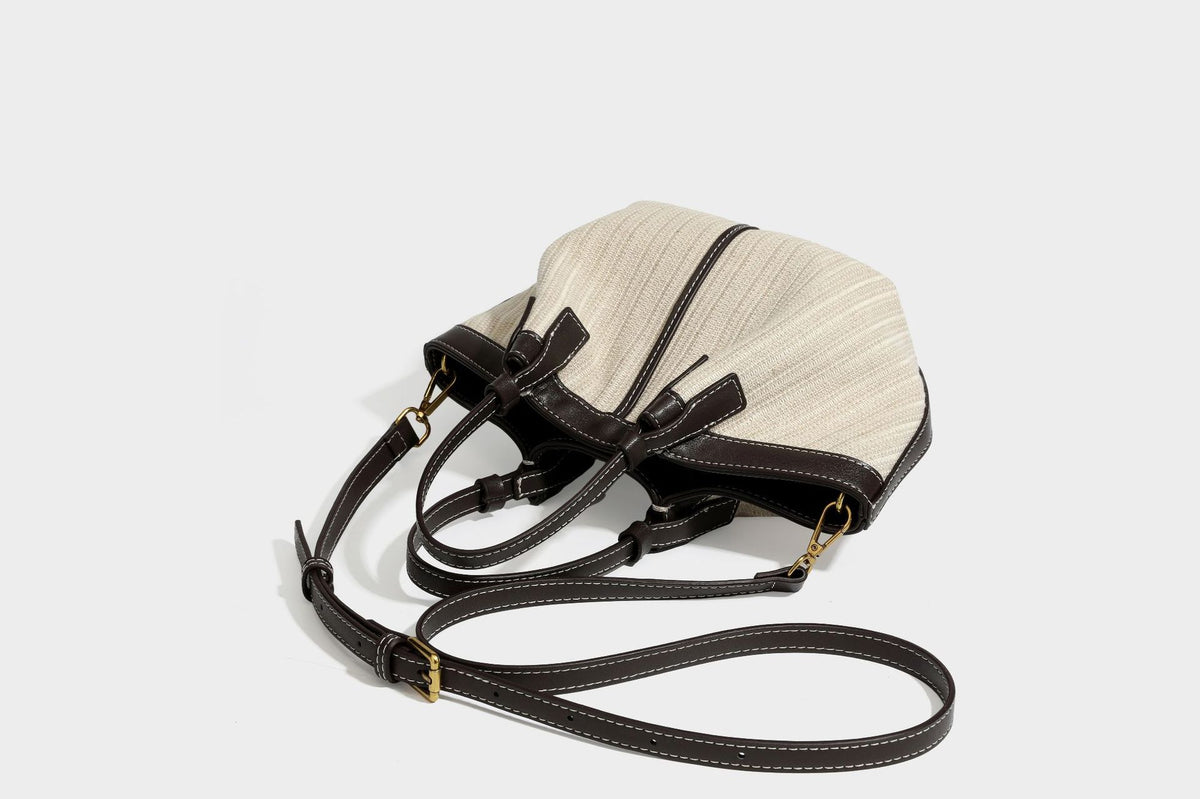 Cremefarbene geflochtene Tote-Bag mit dunkelbraunen Besätzen in Lederoptik, kontrastierenden weißen Nähten, zwei oberen Henkeln und abnehmbarem Schulter
