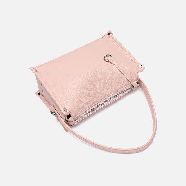 Small structured pebbled-finish convertible bag with silver corner studs, zip top, and detachable shoulder strap, detail view