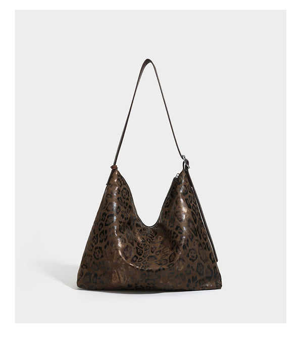 Slouchy leopard print hobo shoulder bag with glossy coated finish, top zipper closure, dark brown trim, and dangling charm