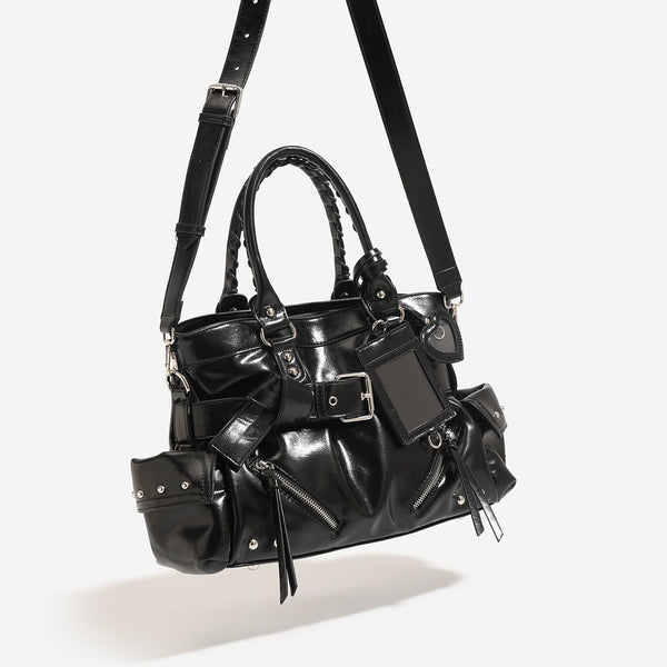 Black glossy leather-look structured tote bag with silver studs, buckle strap, exterior zip pockets, braided top handles