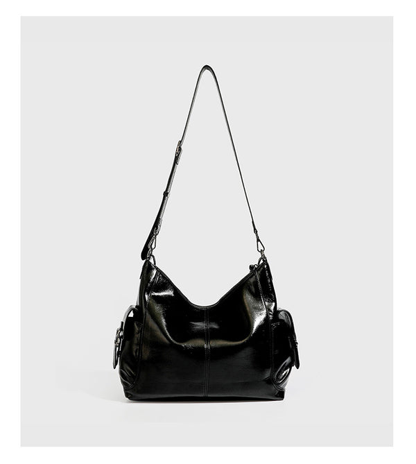 Slouchy hobo shoulder bag with glossy leather-look finish, silver-tone chain drape across front, side buckle pockets, and