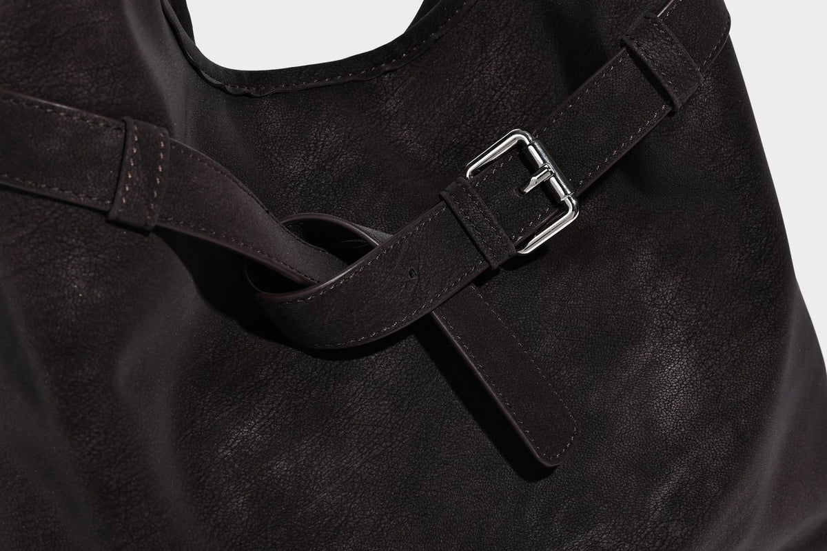 Slouchy oversized shoulder tote bag with matte textured finish, wrap-around buckle strap, and detachable front zip pouch
