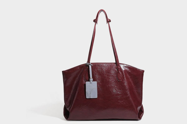 Übergroße, lässig fallende Tote-Bag aus glänzendem, geknittertem Lederimitat in dunklem Burgunderrot mit zwei langen Schulterriemen und kontrastierendem