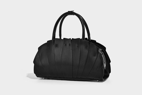 Structured dome satchel with fan-pleated leather-look exterior, dual top handles, and detachable shoulder strap, detail view