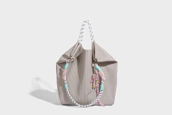 Slouchy pinstripe tote bag with braided rope handles, metal ring hardware, and colorful knotted rope charm, detail view 18