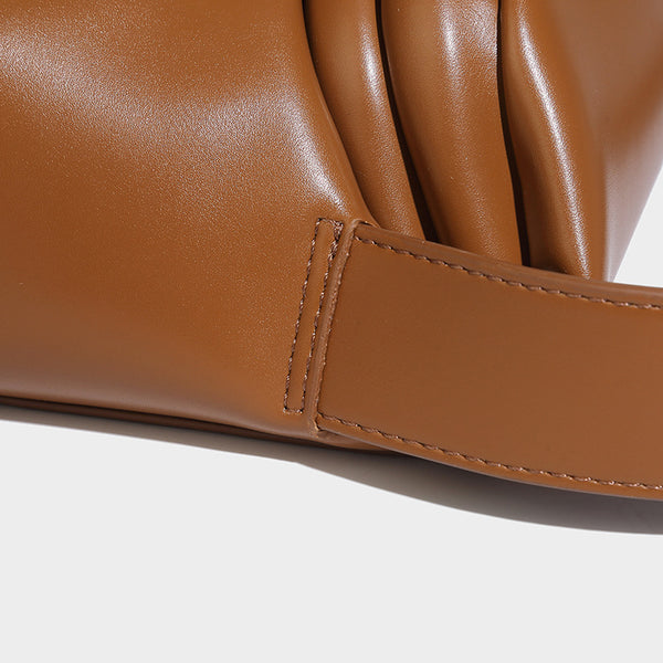 Compact structured baguette shoulder bag with smooth leather-look finish, zip top, and adjustable silver-buckle strap, detail