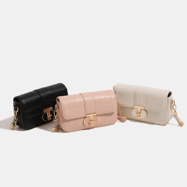 Small crocodile-embossed flap crossbody bag with circular gold turn-lock closure and chain strap, detail view 2