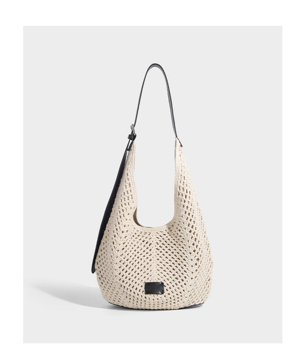 Cream openwork crochet hobo bag with black leather-look strap and trim patch accent, slouchy teardrop silhouette, detail view