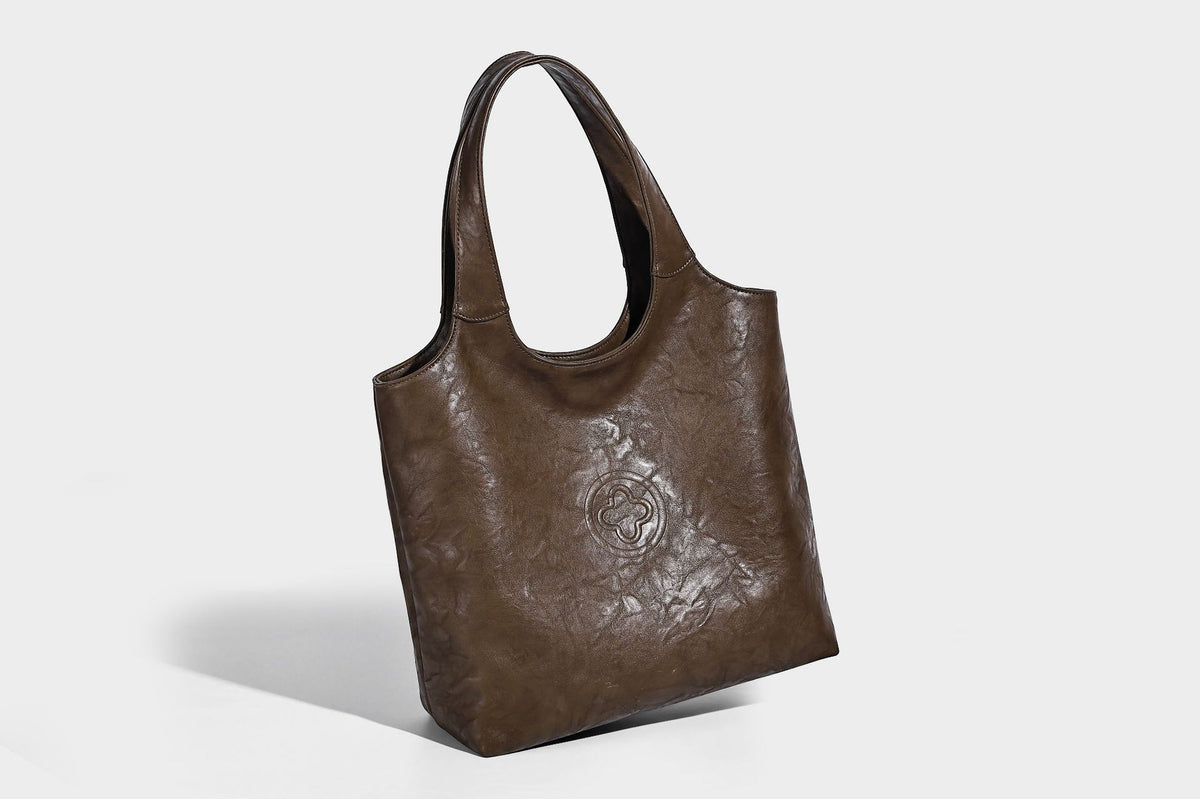 Large open-top tote bag with crinkled leather-look finish, long double shoulder straps, and embossed circular detail on