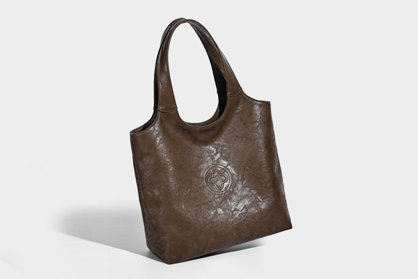 Large open-top tote bag with crinkled leather-look finish, long double shoulder straps, and embossed circular detail on