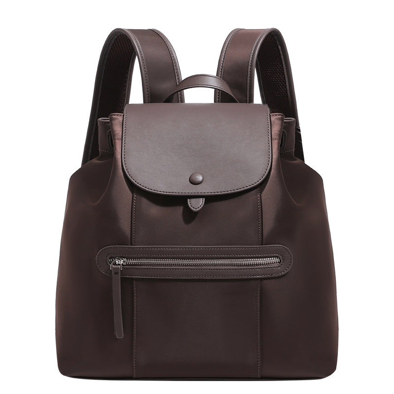 Large flap-top nylon backpack with leather-look trim, snap closure, front zip pocket, and padded shoulder straps, detail view