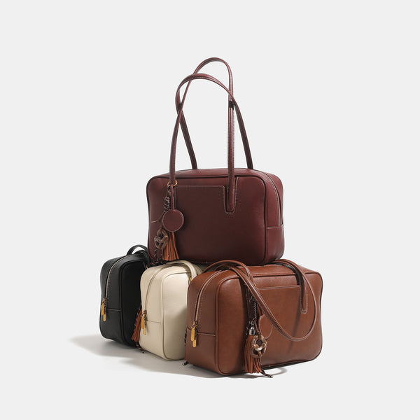 Structured rectangular leather-look shoulder bag with top zip, tassel and resin ring charm, and contrast topstitching, detail