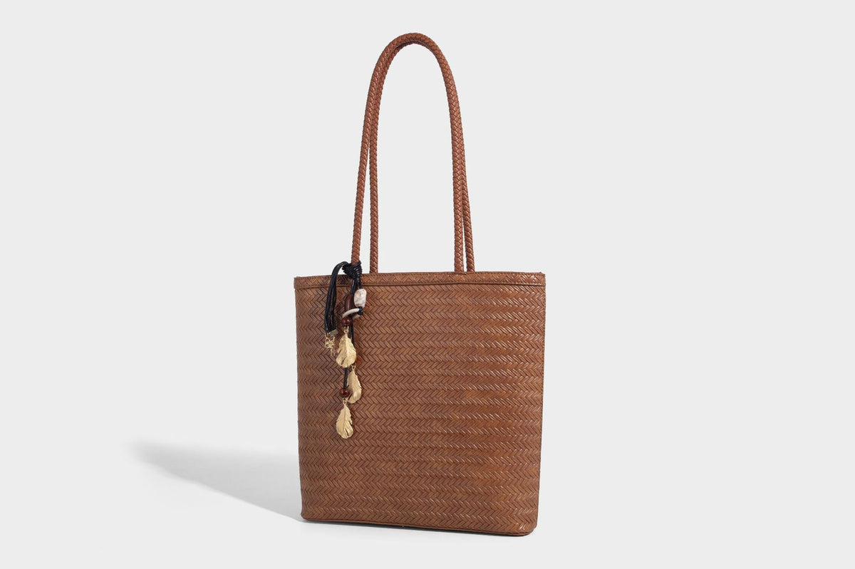 Structured woven herringbone tote bag with braided double shoulder handles in tan brown, shown with matching drawstring