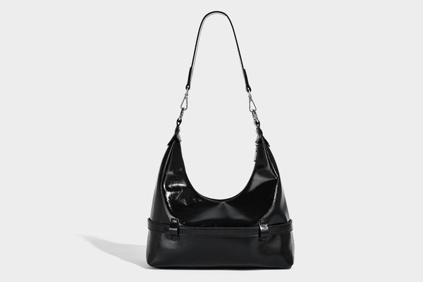 Glossy black slouchy hobo shoulder bag with silver-tone hardware, belt-style grommet strap at base, and long adjustable