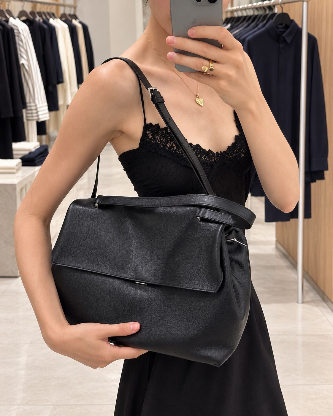 Large black slouchy leather-look shoulder bag with V-shaped envelope flap, silver-tone clasp, and adjustable strap, detail