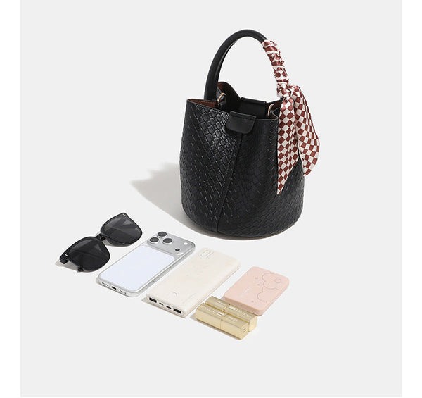 Geprägte Flechtoptik-Beuteltasche mit Verschlusslasche und Druckknopf, kurzem Tragegriff, kariertem Schaldetail und goldfarbenen Beschlägen, Detailansicht