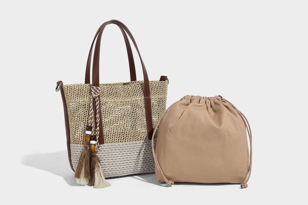 Two-tone open-weave tote bag in beige and cream with brown leather-look handles, tassel bead charm, and detachable