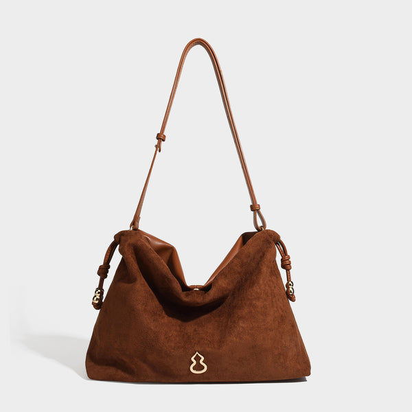 Suede-look drawstring shoulder bag in brown with smooth trim, knotted bead drawstring closure, slim adjustable strap, and