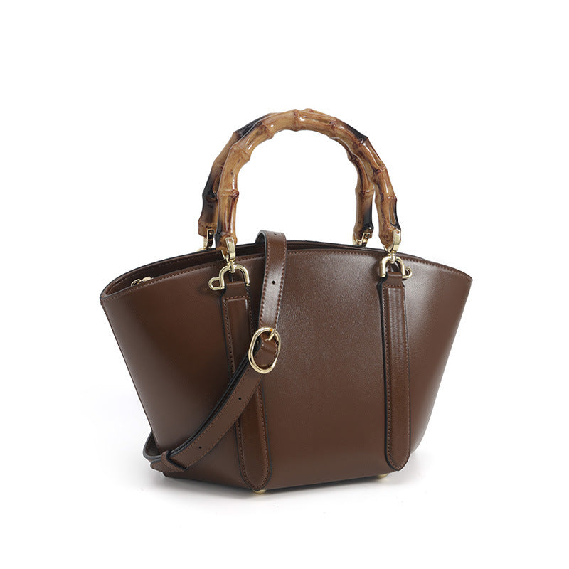 Structured trapezoid handbag with segmented bamboo top handle, smooth leather-look finish, gold-tone hardware, and vertical