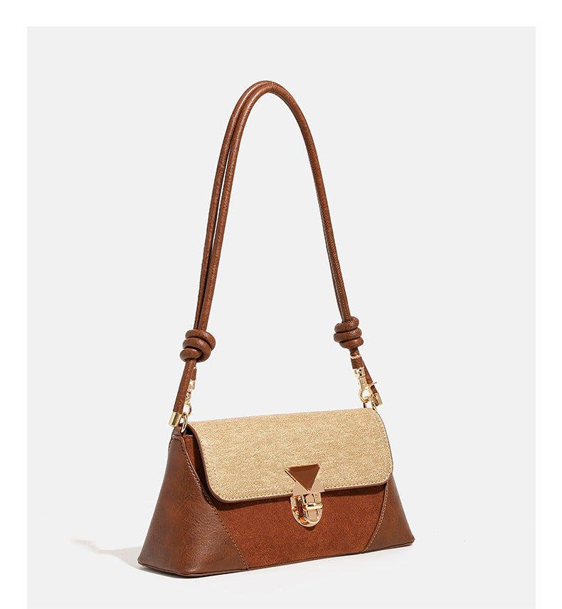 Structured trapezoid shoulder bag with pale textured flap, gold-tone triangular turn-lock closure, and long knotted cord