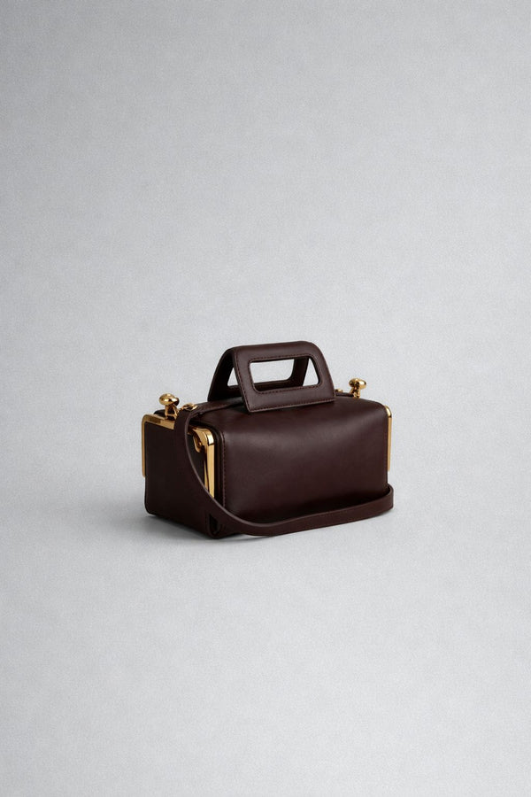 Kompakte dunkelbraune Henkeltasche in Lederoptik mit goldfarbenem Rahmenbeschlag und abnehmbarem, verstellbarem Crossbody-Riemen