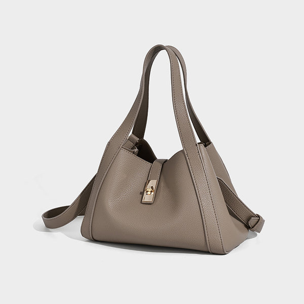 Structured trapezoid tote bag in taupe pebbled leather-look finish with gold-tone turn-lock hardware, dual top handles, and