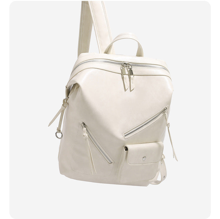 Structured smooth leather-look backpack handbag with dual top zip closure, diagonal front zip pocket, snap-flap mini pocket