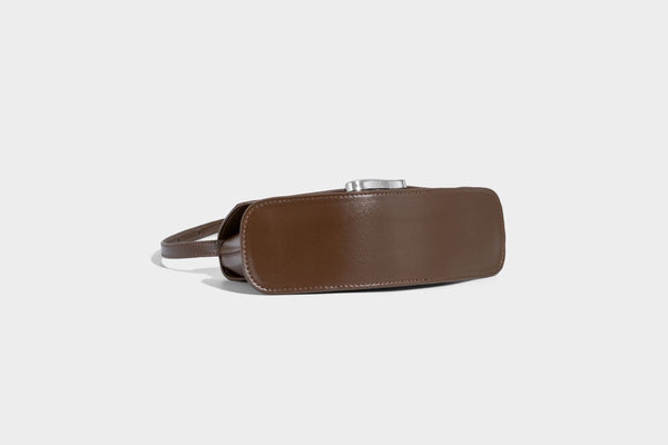 Small structured saddle bag with glossy leather-look finish, angular flap front, silver-tone metal clasp, and slim