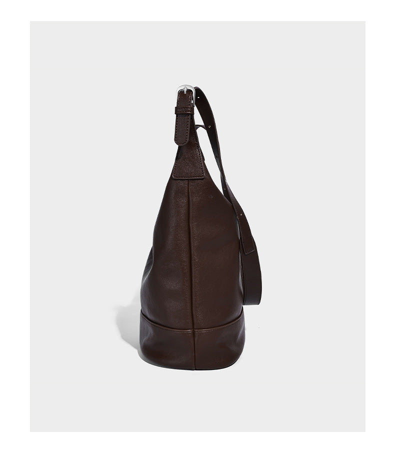 Slouchy bucket hobo shoulder bag in dark brown with glossy leather-look finish, top zip closure, and long adjustable, detail