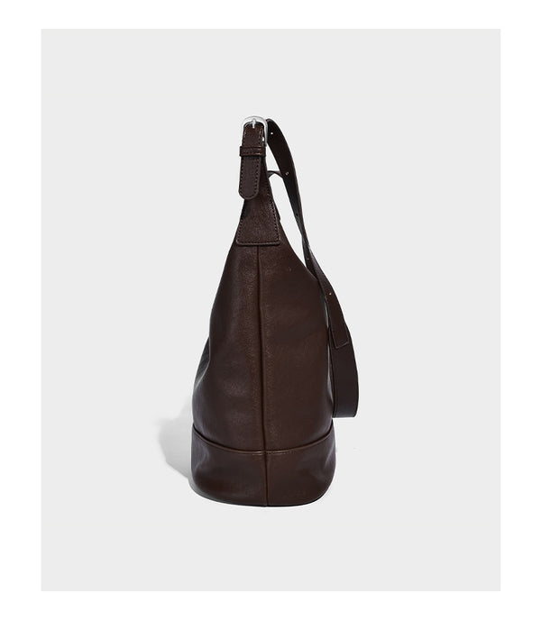 Slouchy bucket hobo shoulder bag in dark brown with glossy leather-look finish, top zip closure, and long adjustable, detail