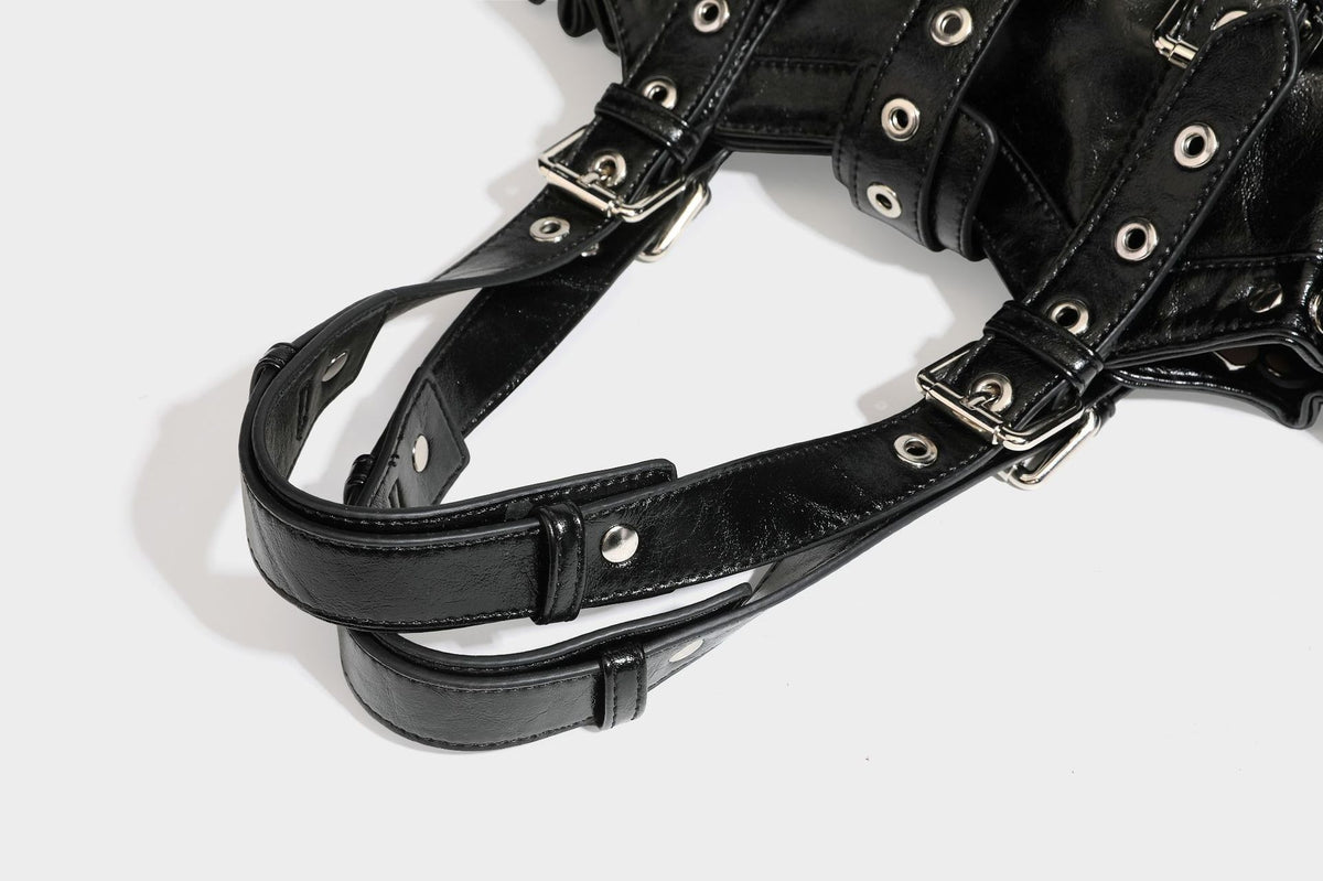 Large black glossy leather-look tote bag with silver buckle straps, eyelet grommet panels, drawstring side gathers, and