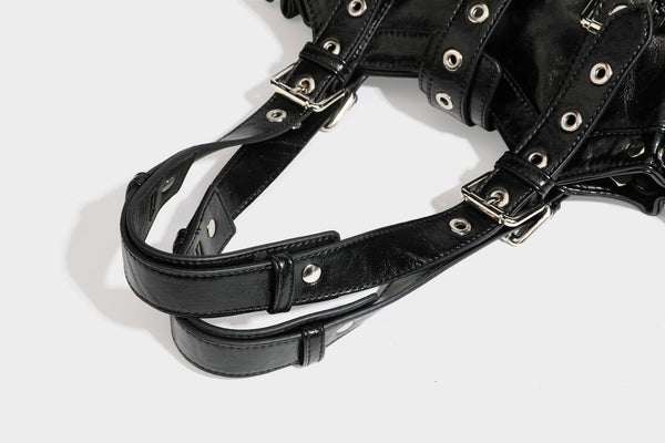 Large black glossy leather-look tote bag with silver buckle straps, eyelet grommet panels, drawstring side gathers, and