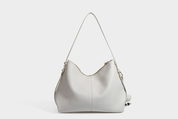 Slouchy hobo shoulder bag with pebbled leather-look finish, zip-top closure, gold-tone hardware, and hanging bead charm