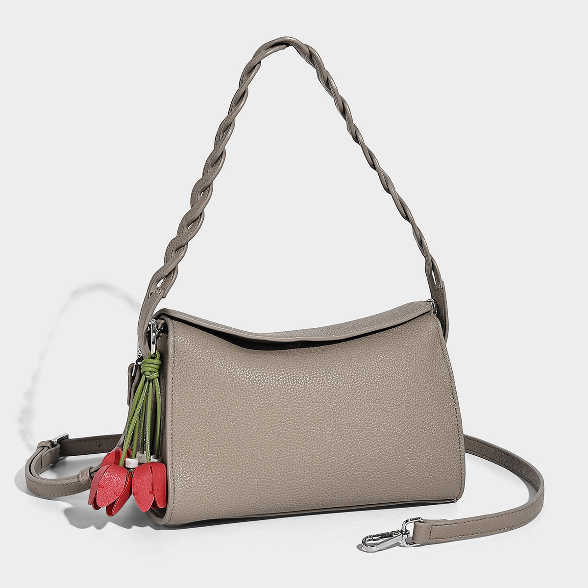 Small structured pebbled-finish shoulder bag with braided top handle, detachable crossbody strap, floral tassel charm, and