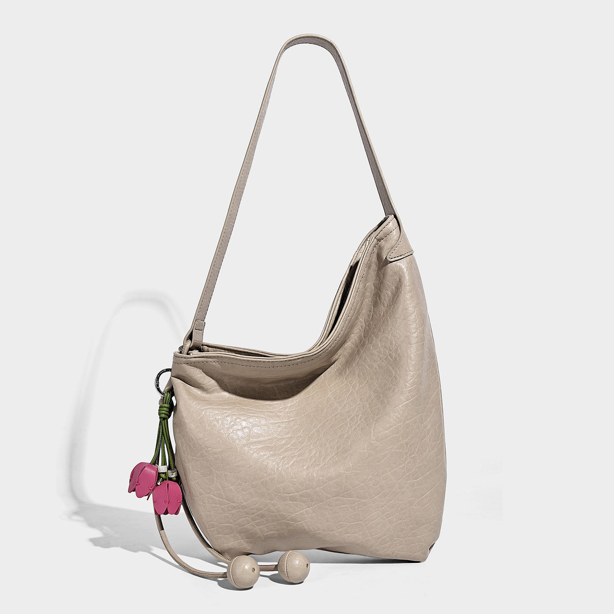 Slouchy hobo shoulder bag in pale yellow with slim strap, drawstring bead closure, and pink tulip floral charm, detail view 9