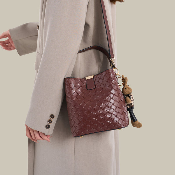 Brown woven-emboss leather-look bucket bag with short top handle, detachable crossbody strap, gold-tone hardware, and rabbit