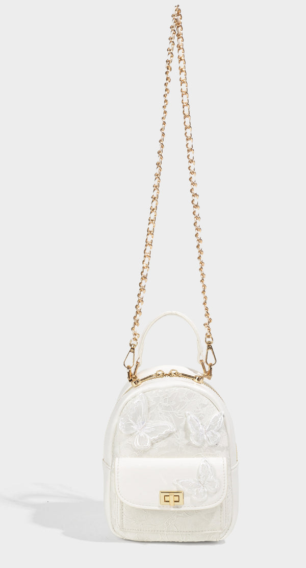 Structured mini backpack handbag with butterfly embroidery, gold-tone chain strap, and turn-lock front flap pocket, detail