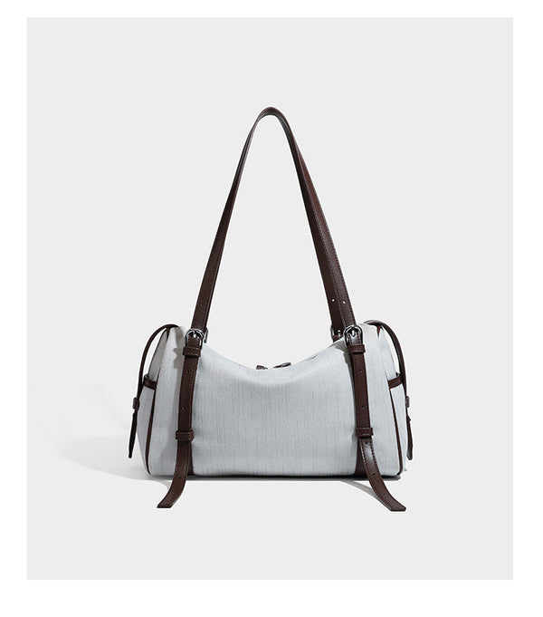 Olivgrüne Schultertasche in Zylinderform aus Canvas mit Riemen in schwarzer Lederoptik, Reißverschluss oben und silberfarbenen Beschlägen, Detailansicht