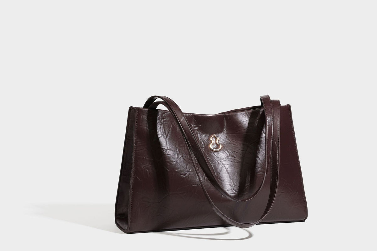 Strukturierte rechteckige Tote-Schultertasche aus glänzender, geknitterter Lederoptik mit langen Doppelträgern und Emblem in Goldoptik